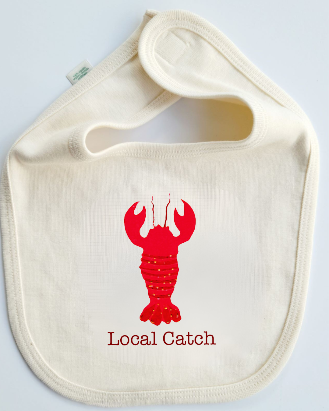 Beige bib with red lobster design and 'Local Catch' text on a light gray background